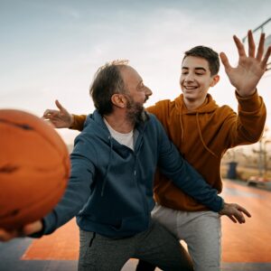 Ein Teenager und ein erwachsener Mann spielen lebhaft Basketball